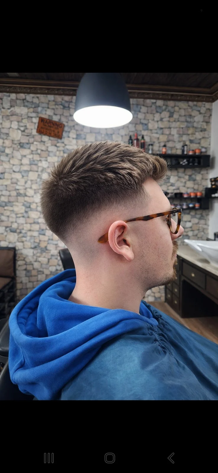 Kurzer Fade mit präzisem Übergang und längerem Deckhaar bei einem Kunden mit Brille